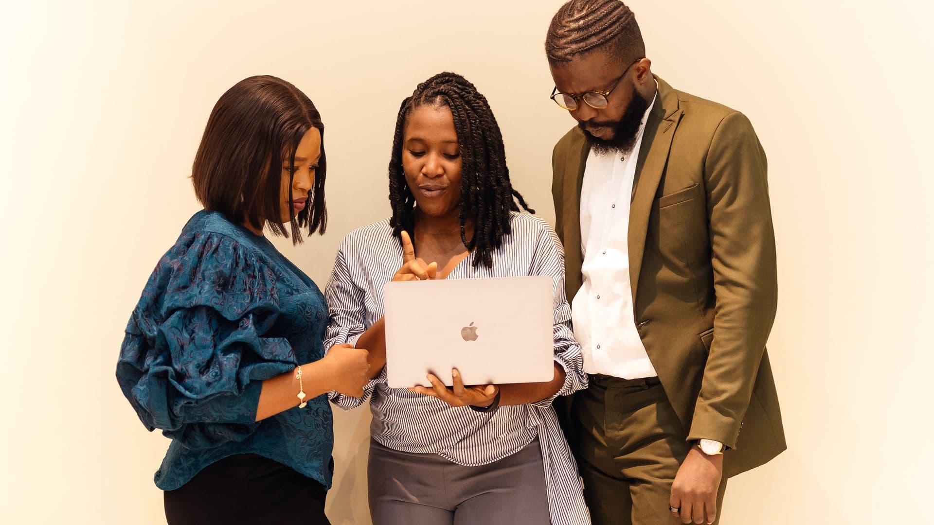 Trois professionnels ouest-africains collaborent autour d'un ordinateur portable.